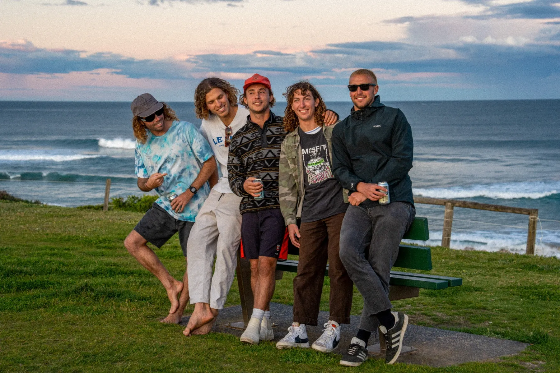The band lined up on the grass above the ocean at dusk